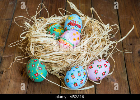 Painted eggs lie in a basket, wooden background, easter Stock Photo