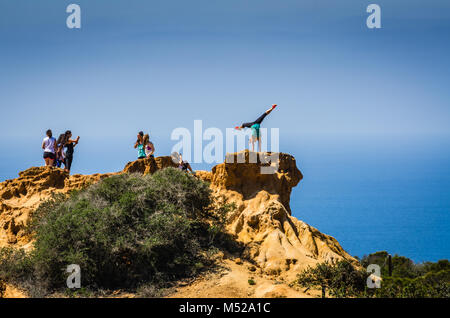 Woman strikes a handstand yoga pose for a photograph on a cliff at Torrey Pines State Natural Reserve, near San Diego, California. Stock Photo