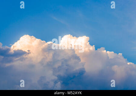 Orange and white clouds illuminated by the rising sun against the blue sky in sunny day after the rain Stock Photo