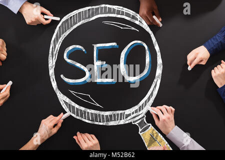 Hands Drawing SEO Search Engine Optimization At Blackboard Stock Photo