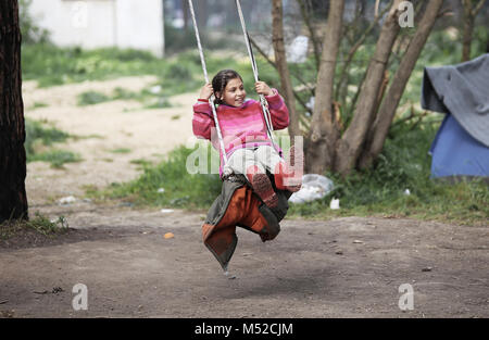 A refugee girl seen enjoying her time on a swing at Idomeni refugee camp. Tens of thousands of refugees are being stuck in Greece as many EU nations has closed their borders to prevent refugees flooding into their territories. Stock Photo