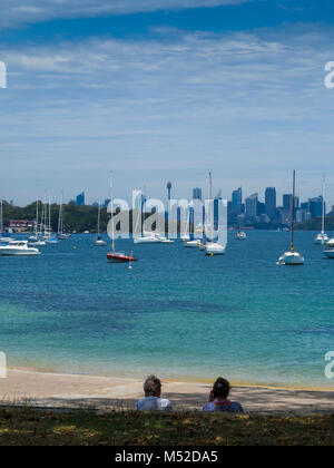 Two people sitting by beach at Watsons Bay taking in the view of Sydney Harbour, New South Wales, Australia Stock Photo