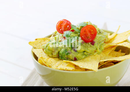 bowl of corn tortilla chips with guacamole dip - close up Stock Photo
