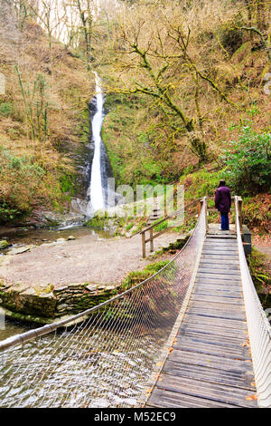 A woman looking at the 30 metre Whitelady waterfall from the suspension bridge over the river Lyd at Lydford Gorge, Devon, England Stock Photo