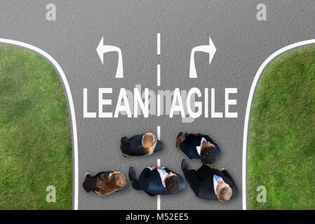 High Angle View Of Businesspeople Standing Near Arrows Showing Lean And Agile Directions Stock Photo