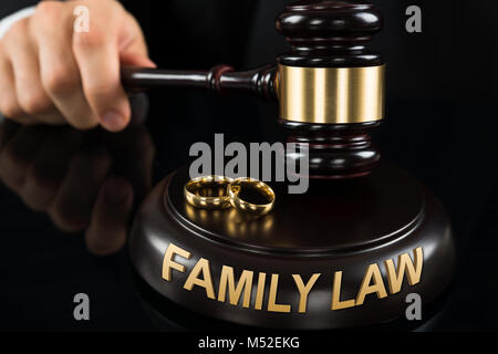 Close-up Of Judges' Hand Hitting Gavel With Golden Rings And Family Law Text At Desk Stock Photo