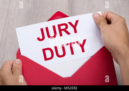 Close-up Of A Human Hand Holding Jury Duty Document In Red Envelope Stock Photo