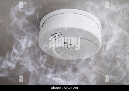 Close-up Of A Smoke Detector On Ceiling Surrounded By Smoke Stock Photo