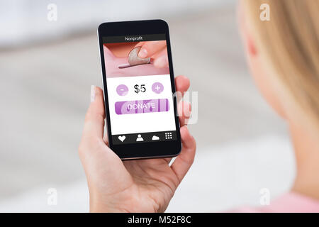 Close-up Of A Business Woman Holding Mobile Phone Donating Money Online Stock Photo