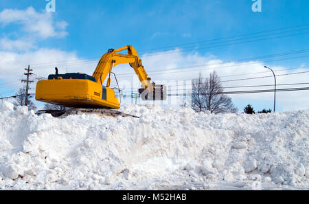 Excavator clearing snow in a parking lot Stock Photo