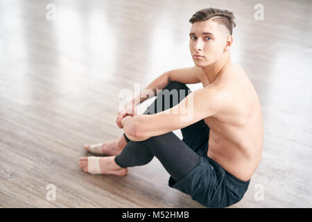 Handsome ballet dancer sitting on the floor and resting Stock Photo