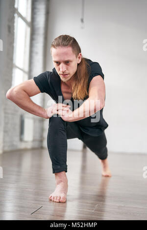 Young fit man stretching legs doing forward lunge. Stock Photo