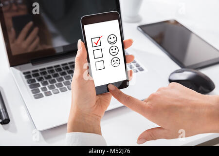 Close-up Of Woman's Hand Selecting Rating On Customer Evaluation Service Form Online Using Mobile Phone Stock Photo