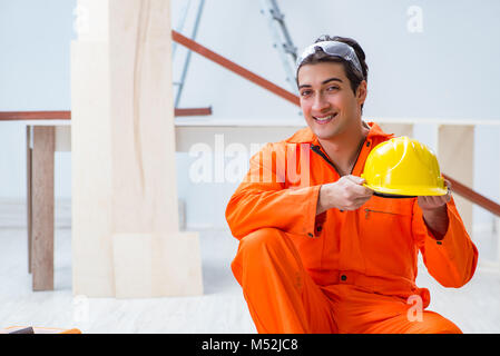 Carpenter wearing yellow hardhat in contractor workshop Stock Photo
