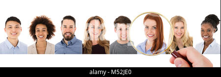 Close-up Of Person's Hand With Magnifying Glass Over Female Candidate For Recruitment Stock Photo