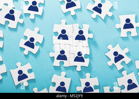 High Angle View Of Human Figures On Jigsaw Puzzles Over Blue Background Stock Photo