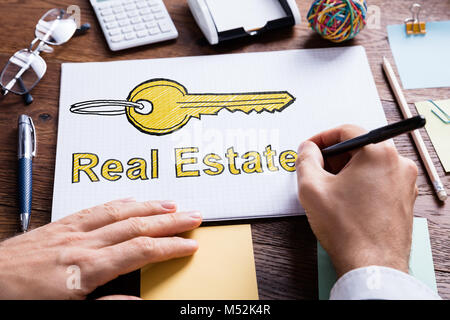 Close-up Of Person's Hand Drawing Real Estate Key On Paper Stock Photo