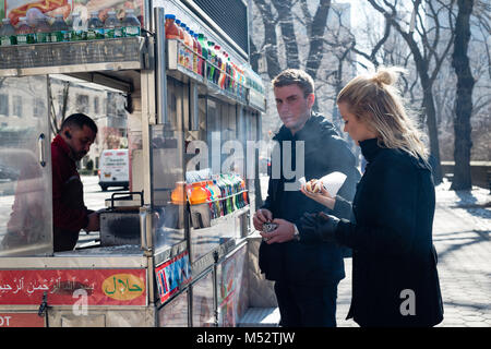 Young blonde couple gets a hot dog in Central Park while on vacation in New York City. Stock Photo