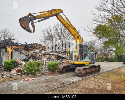 Workers using heavy duty excavator to help demolish a house that caught fire and burned in Montgomery Alabama, USA. Stock Photo