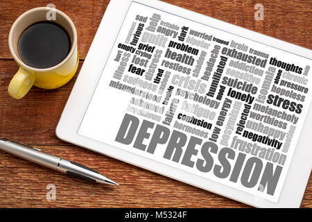 depression word cloud on a  digital tablet with a cup of coffee Stock Photo
