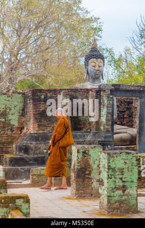 monk walking in prayer among temples of sukhothai thailand Stock Photo