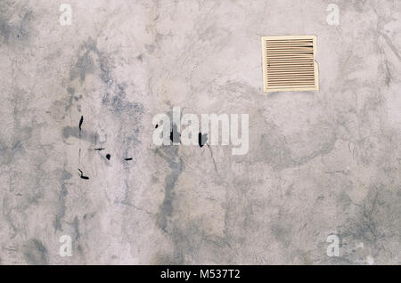 old grey concrete garage wall with spots of black paint with white ventilation grille abstract background Stock Photo