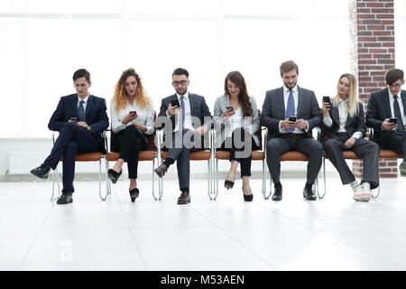 employees with smartphones sitting in the lobby Stock Photo