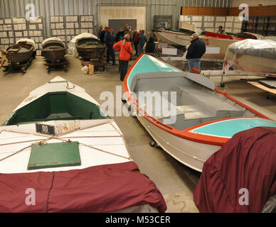 Grand Canyon History Symposium Historic Boat Tour . View of historic boats. Edith, Marble, Music Temple, the Stone Boat, Esmeralda II, WEN in the museum collection storage area. [Foreground are two boats: WEN is white with green trim; and the Music Temple is white with red trip and tourqoise decks. Background are visitors listening to Tom Martin while standing near the Edith, Marble, the Stone Boat, and  Esmeralda II.]  The Grand Canyon Historical Stock Photo