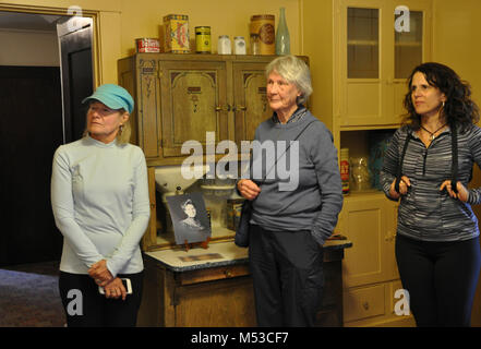 Grand Canyon History Symposium Historic Kolb Studio . View of three members listening to Phil Payne speak about the family kitchen in the residence. [Three female members standing in kitchen in front of cupboard; yellow walls, facing left and listening Stock Photo