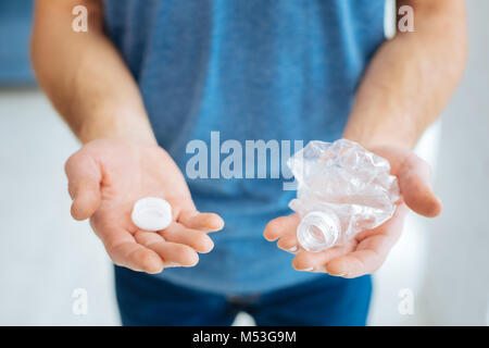 Male hands holding a crushed plastic bottle Stock Photo