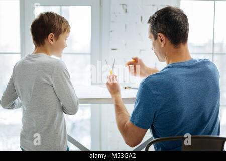 Young engineer showing his son how to work with compass Stock Photo