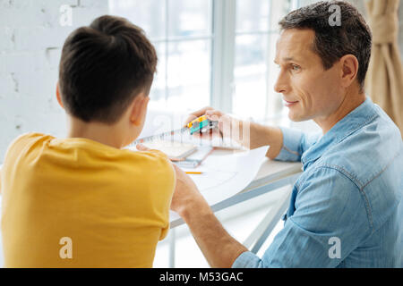 Young father showing tape measure to his son Stock Photo