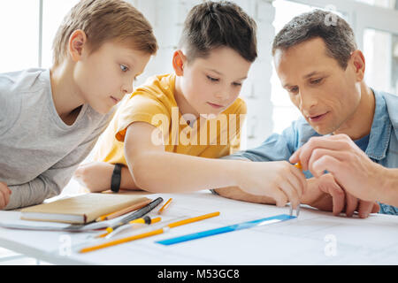 Pleasant father showing son how to use compass correctly Stock Photo