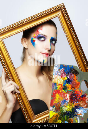 Young woman painter in golden frame with color palette in hand Stock Photo