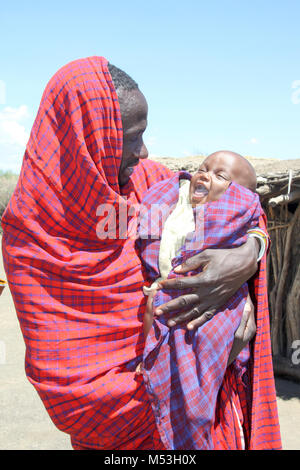 Masai father carrying child in his arms, Ngorongoro Conservation Area, Tanzania. Stock Photo