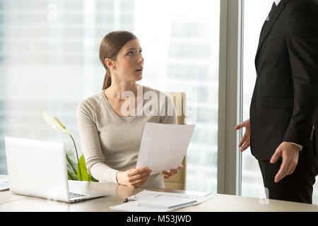 Young woman listening claims on her work from boss Stock Photo