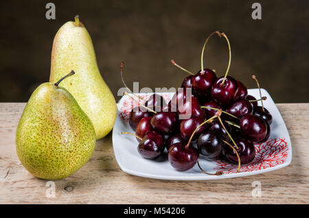 berries cherries in a plate and pears on a table Stock Photo