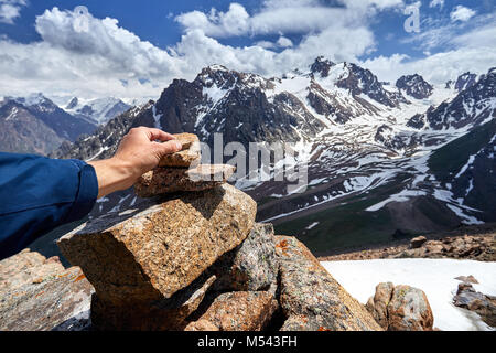 Traveler putting stone on the pyramid in the snowy mountains Stock Photo