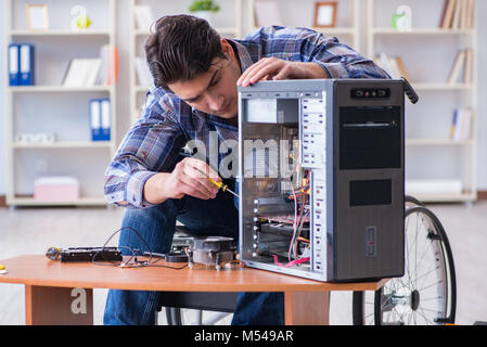 Disabled man on wheelchair repairing computer Stock Photo