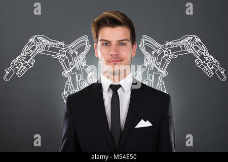 Young Businessman With Robotic Arms On Background Stock Photo