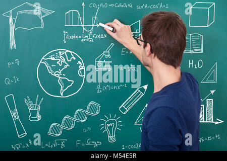 Male Teacher Teaching Physic Equation On Chalkboard In Classroom Stock Photo
