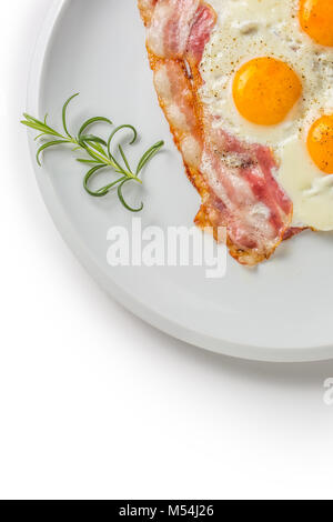 Ham and Eggs. Bacon and Eggs. Salted egg with pepper on white plate. English breakfast. Stock Photo