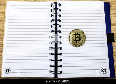 Cryptocurrency physical golden bitcoin. Golden bitcoin on notebook background. 3D illustration. Stock Photo