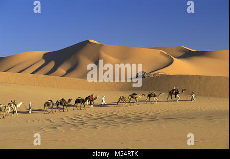 Algeria. Near Djanet. Sahara desert. Men of Tuareg tribe and camel caravan. Sand dunes and sand sea. Stock Photo