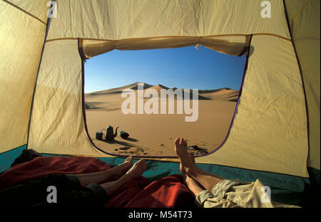 Algeria. Near Djanet. Sahara desert. Sand dunes. Feet of couple in tent. Camping kettle and accessories. Campfire. Couple in tent in desert, desert vi Stock Photo