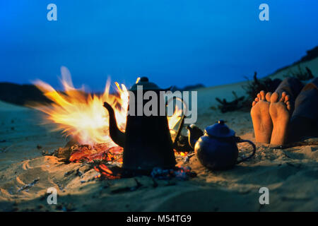 42-15295946Algeria, Djanet. Sahara desert. Coffeepot, teapot and feet warming by campfire. Stock Photo