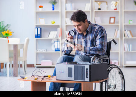 The computer repairman on wheelchair working Stock Photo