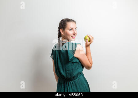 Girl looks over shoulder and eats apple Stock Photo