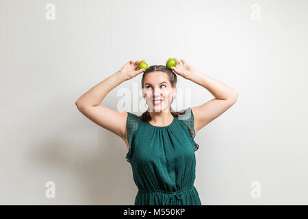 Pretty young girl looks to side and holding limes on head Stock Photo