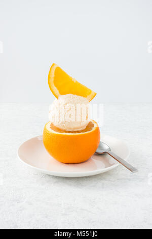 Scoop of homemade orange ice cream served on an orange and decorated with an orange slice. Stock Photo